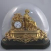 PENDULE en bronze et régule doré sous son globe en verre