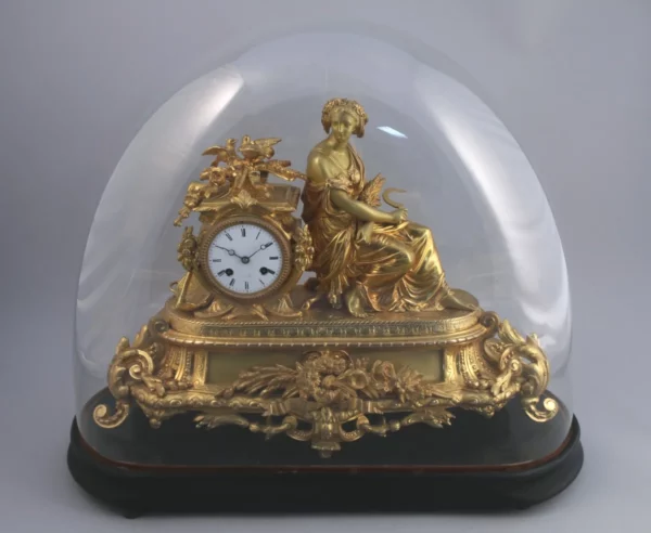 PENDULE en bronze et régule doré sous son globe en verre